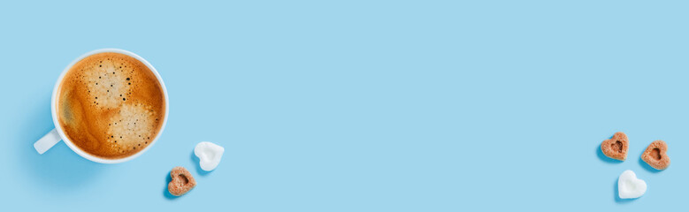 Morning cup of strong coffee with five pieces of sugar in the shape of hearts on blue background.