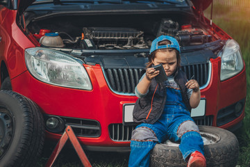 Plakat child with electrical appliance in hands trying fix broken car