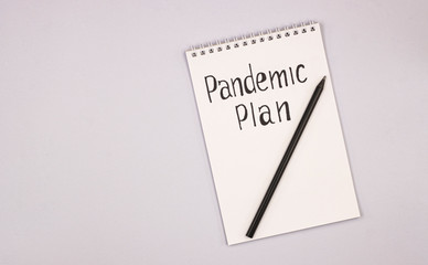 a white notebook with a pencil and the words pandemic plan. the concept of building a different plan because of the coronavirus pandemic