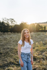 Beautiful happy woman in the field at sunset