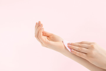 Make up removal pad, absorbent for micellar water, cotton sponge. Nail polish remover in woman's hands on pink background.