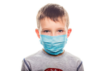 Little boy in a disposable mask on a light background. Kid is wearing the mask for protect them self from virus and air pollution