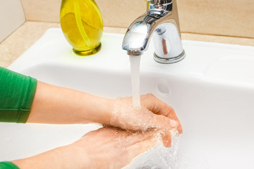 A Hands with soap are washed under the tap with water. Clean from infection and dirt and virus. At...
