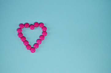 heart of pink buttons on a mint background with copy space