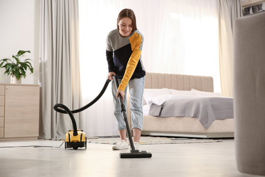 Young woman using vacuum cleaner at home