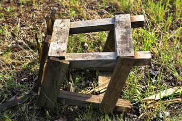 An old broken wooden chair lies on the grass in an abandoned garden