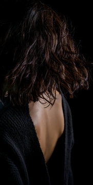 Close-up detail photo of young woman wearing open back blouse on black background