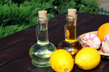 Olive oil and sunflower oil in decanter on a brown wooden table. Limons and garlic on a wooden background. Healthy food. Carafe with oil. The oil container. Vitamins. Rustic style.