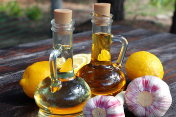 Olive oil and sunflower oil in decanter on a brown wooden table. Limons and garlic on a wooden...