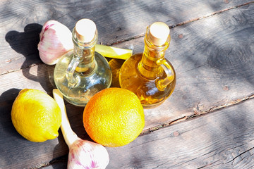 Olive oil and sunflower oil in decanter on a brown wooden table. Limons and garlic on a wooden...