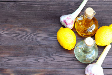 Olive oil and sunflower oil in decanter on a brown wooden table. Limons and garlic on a wooden...