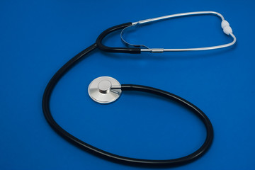 Black stethoscope on blue background.