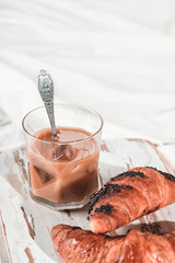 A cup of cold espresso coffee with cream and waffle tubule with chocolate filling in bed. Sweet breakfast, copy space for your text