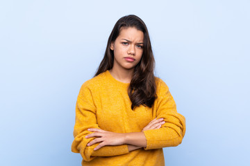 Young Colombian girl with sweater over isolated blue background feeling upset