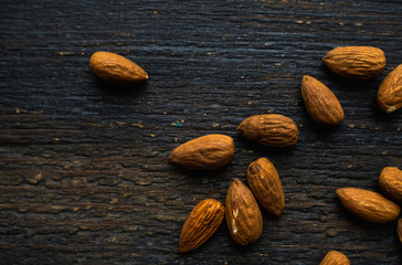 Almonds scattered on the wooden vintage table. Almond is a healthy vegetarian protein nutritious food. Almonds on rustic old wood.