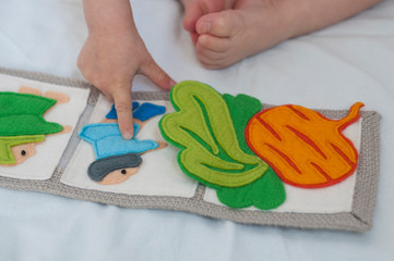 Baby playing with handmade textile book. Child pointing with her finger at a book with funny felt...