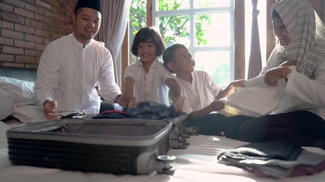 asian family prepare clothes and put in suitcase for carried when mudik go to back village home