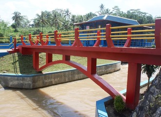 Fototapeta na wymiar a bridge with red yellow and blue colors in temanggung district, central java at noon. water flows in a river under the bridge