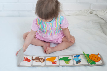 Baby playing with handmade textile book. Child opening an ineractive book with funny felt toys. Early development. Colourful educational toy.