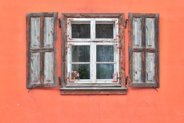 Fototapeta na wymiar Window frame with shutters on a pink facade.