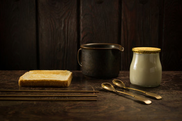 bread, a yogurt and spoons on a wooden background