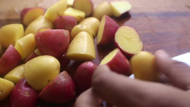 Person&rsquo;s hands preparing potatoes on wooden cutting board
