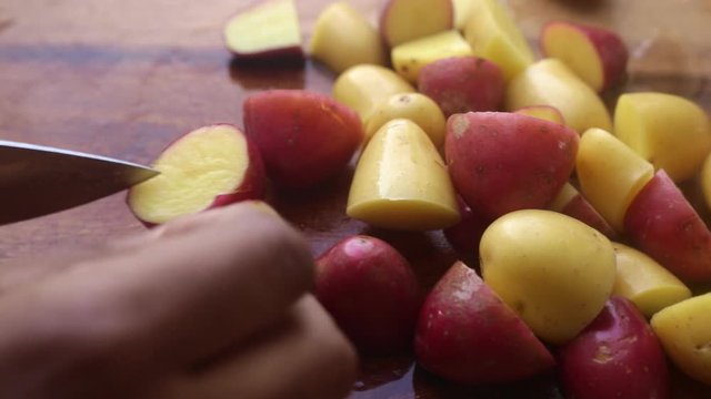 Person&rsquo;s hands preparing potatoes on wooden cutting board