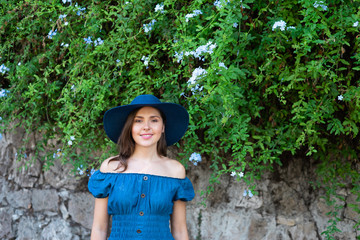 Young and beautiful brunette girl in dress and hat walking outdoor in the park. Nice, France. Summer vacation, traveling and tourism.