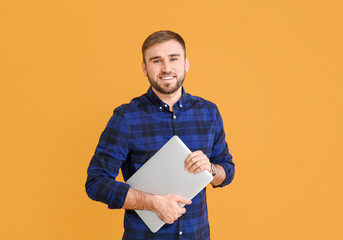 Male programmer with laptop on color background