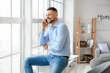 Handsome businessman talking by mobile phone in office