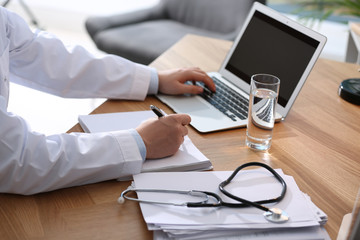 Professional doctor working on laptop in office, closeup