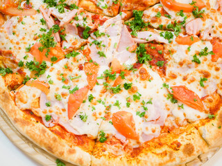 large view of pizza with bacon tomatoes and herbs.