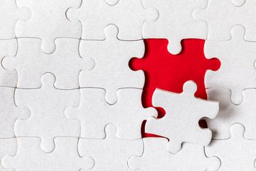 White jigsaw puzzle. White puzzle pieces on color background. Unfinished white jigsaw puzzle pieces on color background.