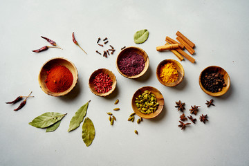 Various colorful spices in wooden bowls on concrete background. Top view. Different types of...