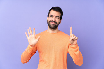 Fototapeta premium Caucasian handsome man over isolated purple background counting six with fingers