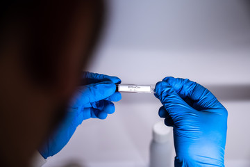 laboratory technician at work showing a sterile test tube containing a sample to study the coronavirus covid 19