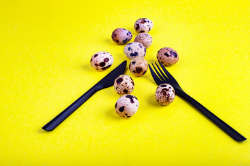 Beautiful yellow background with quail eggs. Food background with knife and fork. Quail eggs.