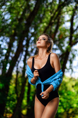 Attractive blonde in a black bodysuit posing in a park