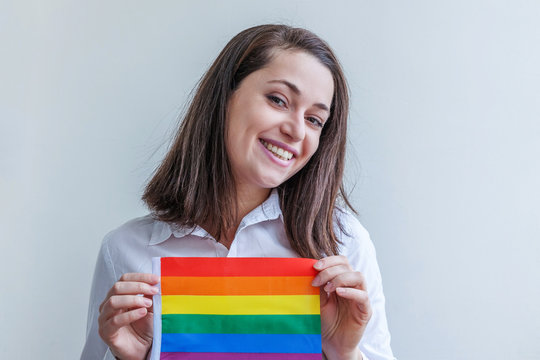 Beautiful caucasian lesbian girl with LGBT rainbow flag isolated on white background looking happy and excited. Young woman Gay Pride portrait. Equal rights for lgbtq community concept.