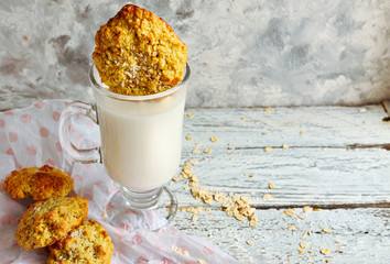 Oatmeal cookies and a glass of milk. Dip cookies in milk. Light wooden background. Healthy sweet breakfast. Free space for text.