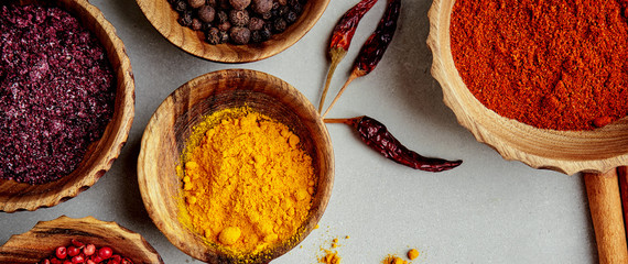 Close-up view of various colorful spices in wooden bowls on a concrete background. Top view....