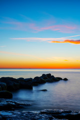 Fototapeta na wymiar Amazing cloudy spring sunset over deep blue ocean and endless horizon, with boulders in the foreground island of Gotland in the Baltic Sea, Sweden