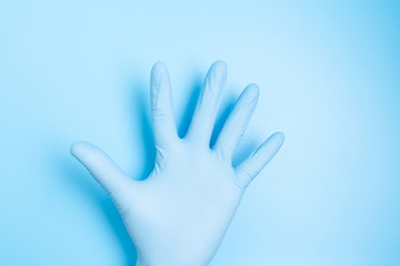 Male palm in medical latex hand glove isolated on blue background, high five sign