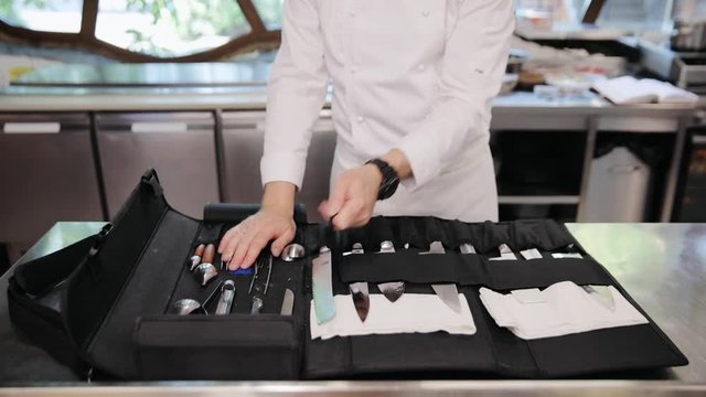Male chef preparing his professional cooking knives at restaurant. Man's hands take knife from knives set. Professional kitchen knives concept