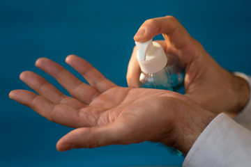 Sanitizer gel. Hand antiseptic. blue bottle of antibacterial product in man's hands on a blue background.epidemic of coronavirus. Hygiene and health concept.