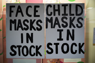 Adult and child face masks in stock hand written signs in a pharmacy window during the coronavirus covid-19 lockdown.  