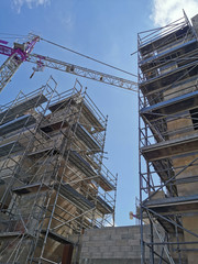 Fototapeta na wymiar building crane and building under construction in scaffolding against the blue sky