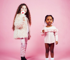 lifestyle people concept: diverse nation children playing together, caucasian and african american on pink background