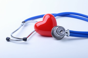 Medical stethoscope and red heart isolated on white.