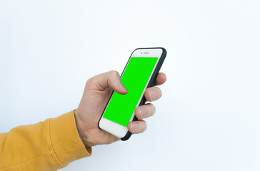 Close-up of a man's hand in a yellow sweater holding green mock-up screen smartphone. Isolated on white background. Modern Mobile Phone